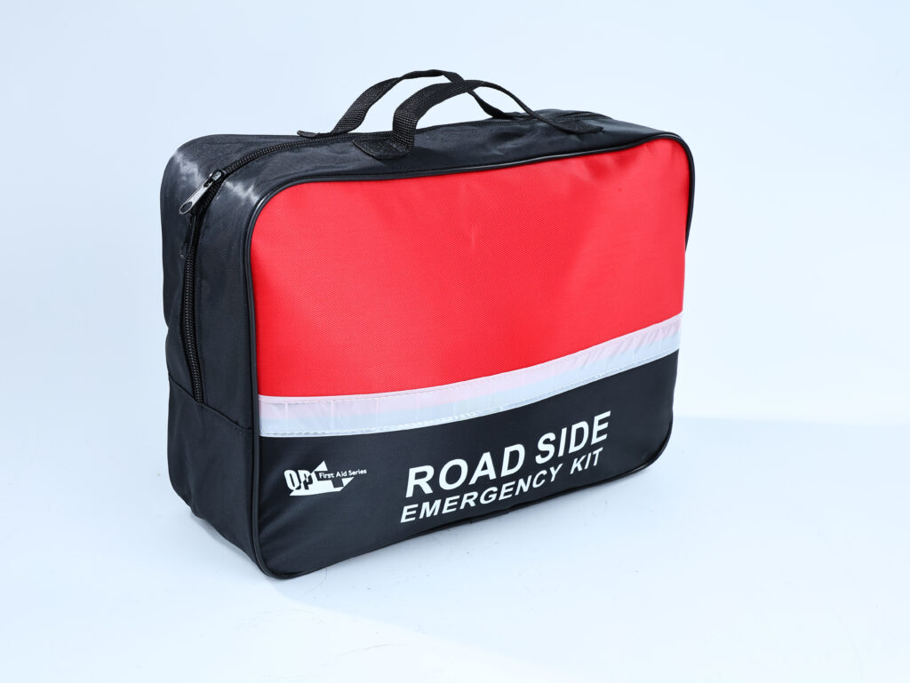 Gros plan d’un sac de trousse d’urgence en bordure de route, avec un motif rouge et noir avec une bande réfléchissante.